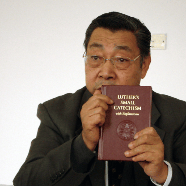 Pastor Holding Luther's Small Catechism