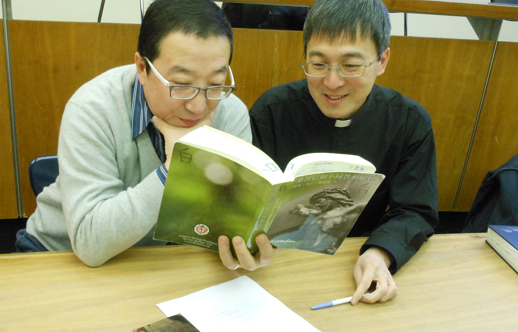 Chinese Man And Pastor Reading Luther's Small Catechism