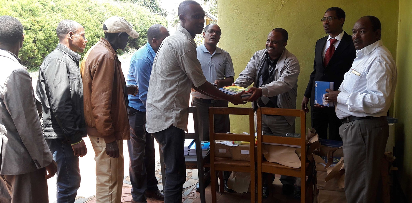 Men receiving stacks of books in Africa