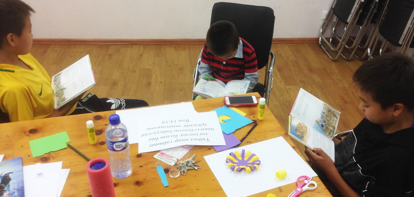 Mongolian Children Reading A Child's Garden of Bible Stories In Classroom