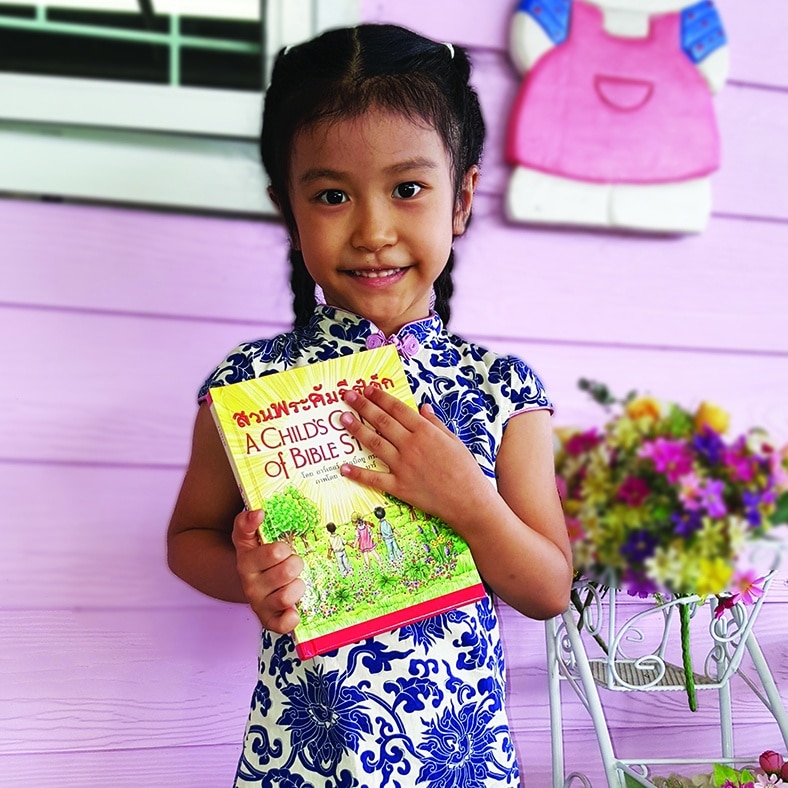 Thai GIrl holding A Child's Garden of Bible Stories