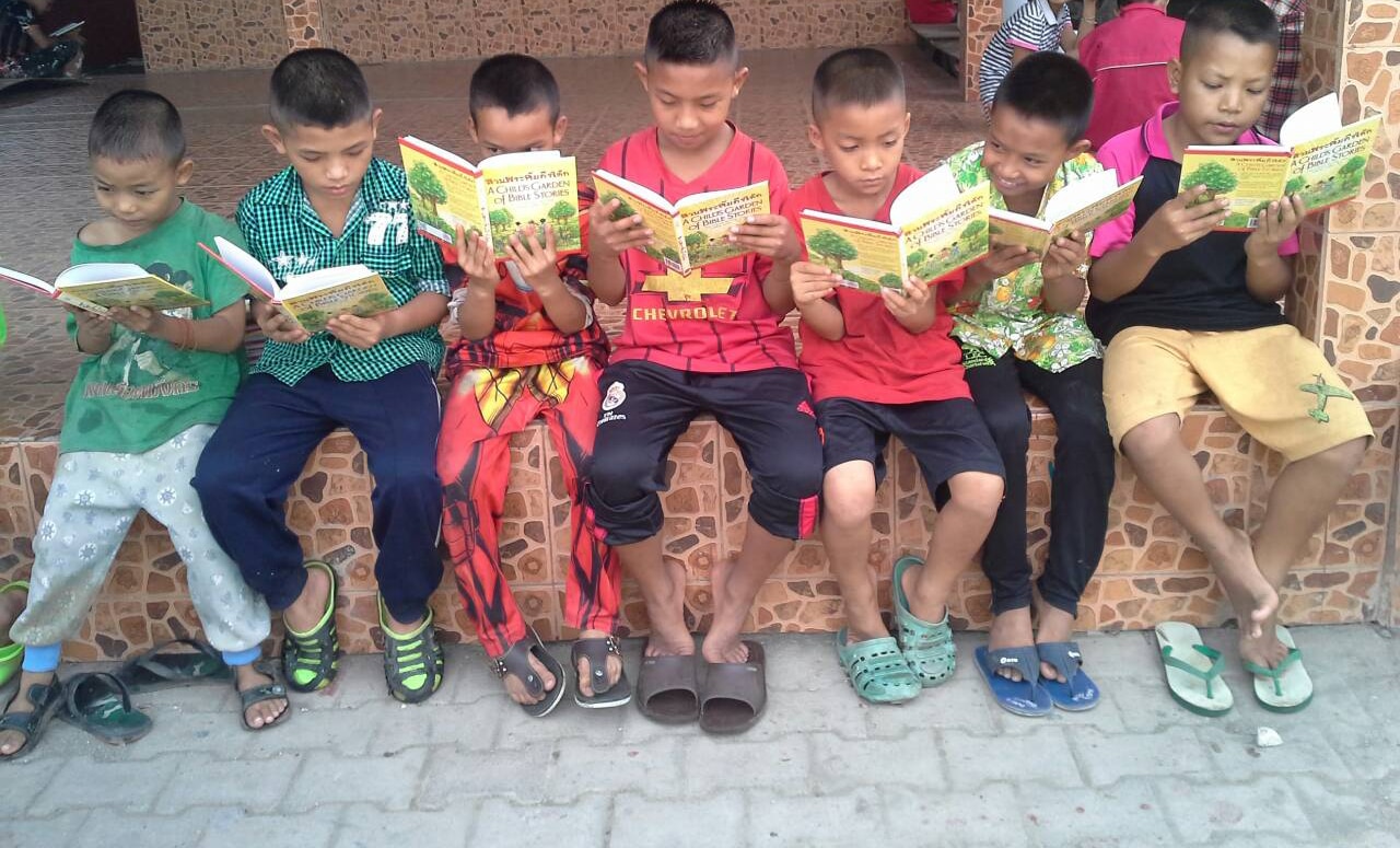 Thai boys reading A Child's Garden of Bible Stories