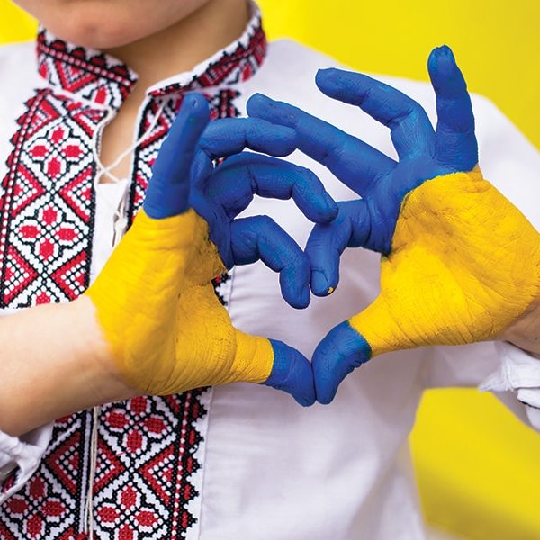 Children against war. Russia's invasion of Ukraine, request for help from world community. child against background of Ukrainian flag with hands in shape of a heart, painted in yellow and blue